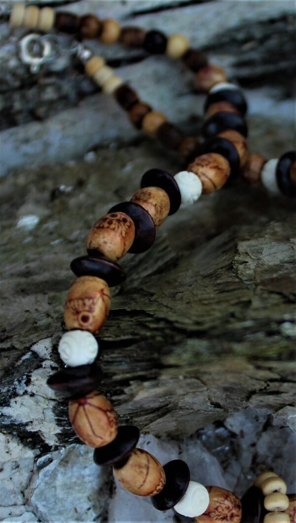 Close-up of the Bonnie beaded necklace featuring brown, black, and white beads, set on a textured stone surface.