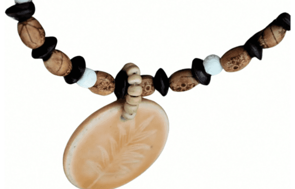 The "Bonnie" necklace features a large tan oval pendant engraved with a leaf design, complemented by black, brown, and white beads.